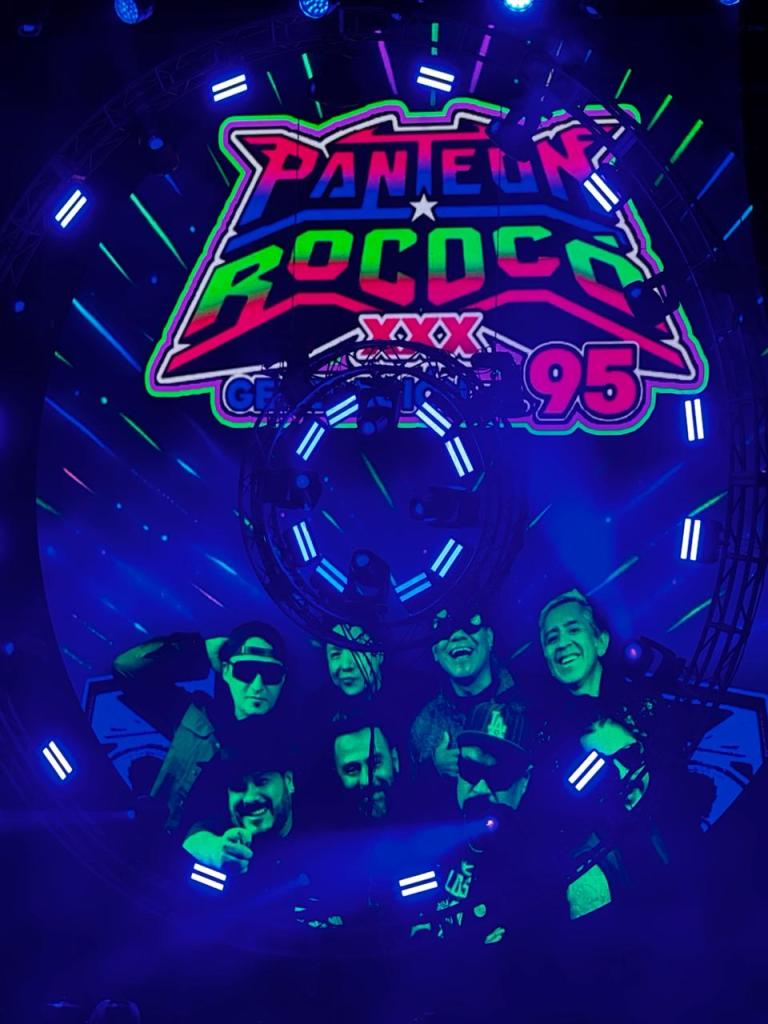 Pantheon Rococo XXX en un escenario iluminado con luces coloridas y un fondo vibrante con el logotipo de la banda.